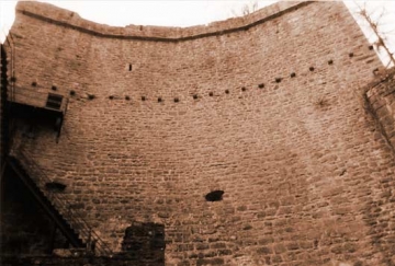 10 Die Schildmauer vom Burghof her. Auf den 22 Konsolsteinen fußten entweder schräge Stützbalken eines Wehrganges, oder war an ihnen "ein Laufgang aufgehängt" (Antonow; vgl. dazu Dähn 1986). Beidseits laufen um die Mauer herum 4 bzw. 7 Konsolsteine. Links oben, 9 m über dem Hofniveau, der Hocheingang in das Treppenhaus der Schildmauer.