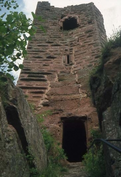 05 Aufgang zum Wohnturm, Rundbogenpforte mit 'späterem Türfalz', spitzbogiges Schlitzfenster mit kunstvoll gebuckeltem Gewände, darüber großes ausgebrochenes Fenster aus dem ersten Wohngeschoss.